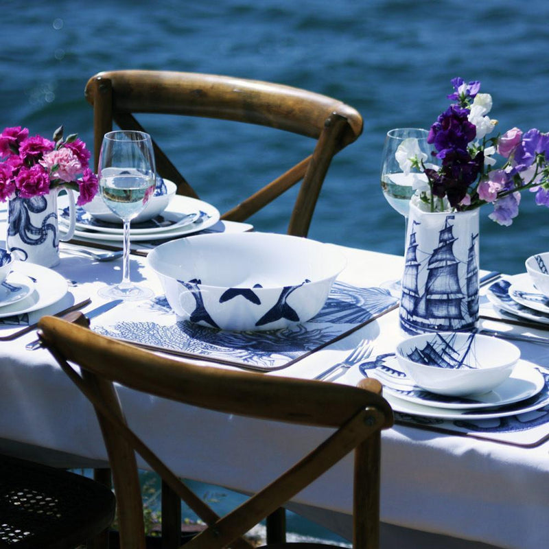 Serving bowl in Bone China in our Classic range in Navy and white in the Lobster design on a white tablecloth on a table setting in the background you can see the sea