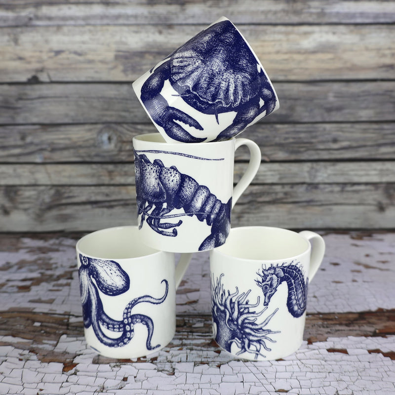 The photo shows Bone china white mug featuring hand drawn lobster design in classic Navy stacked with our other classic mugs,crab,Octopus and Seahorse