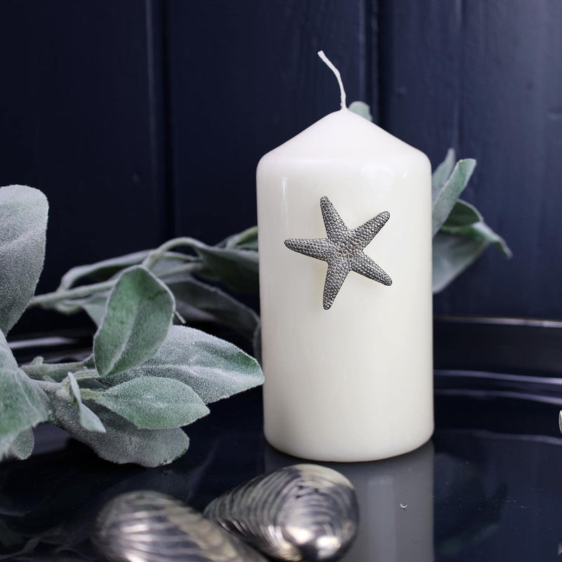 Pewter Starfish Candle Pin decoration placed onto a thick white candle placed on a table next to other Pewter items